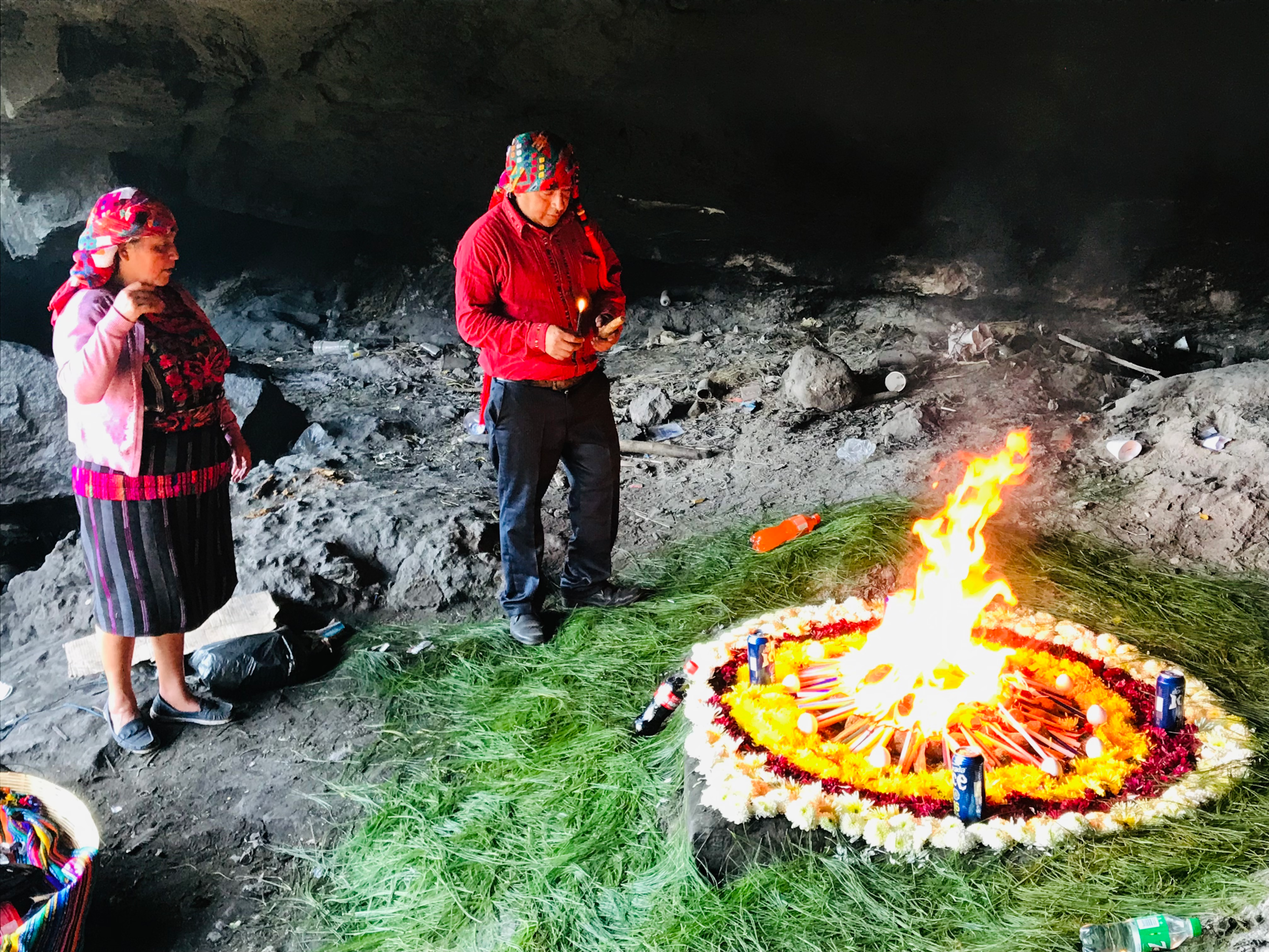 Mayan shaman and his assistant stood around a newly-lit fire inside the sacred caves