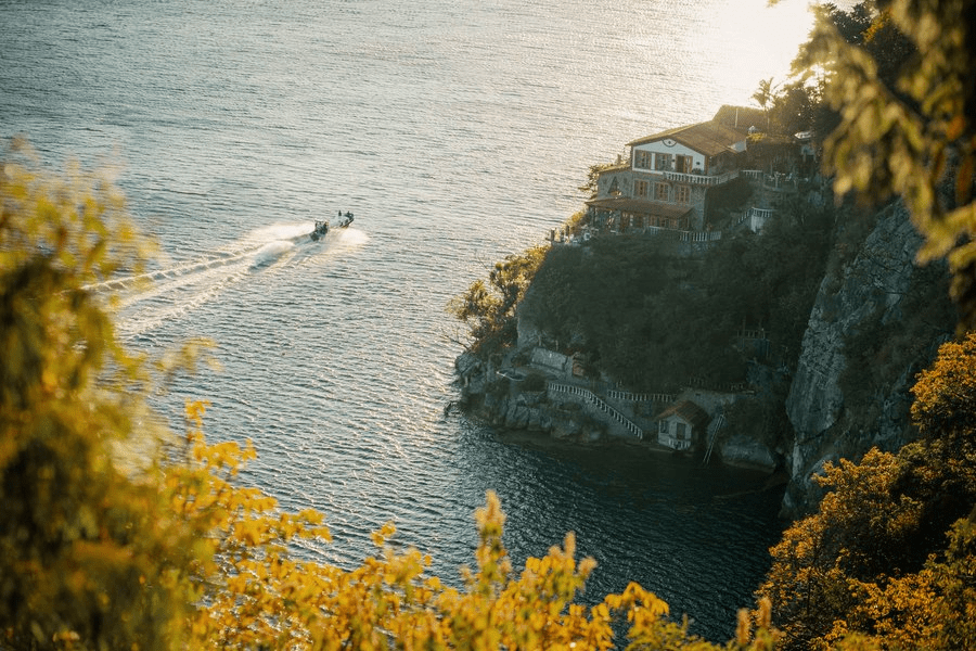 Casa del mundo and the lake photographed from behind bushes on the cliff edge.